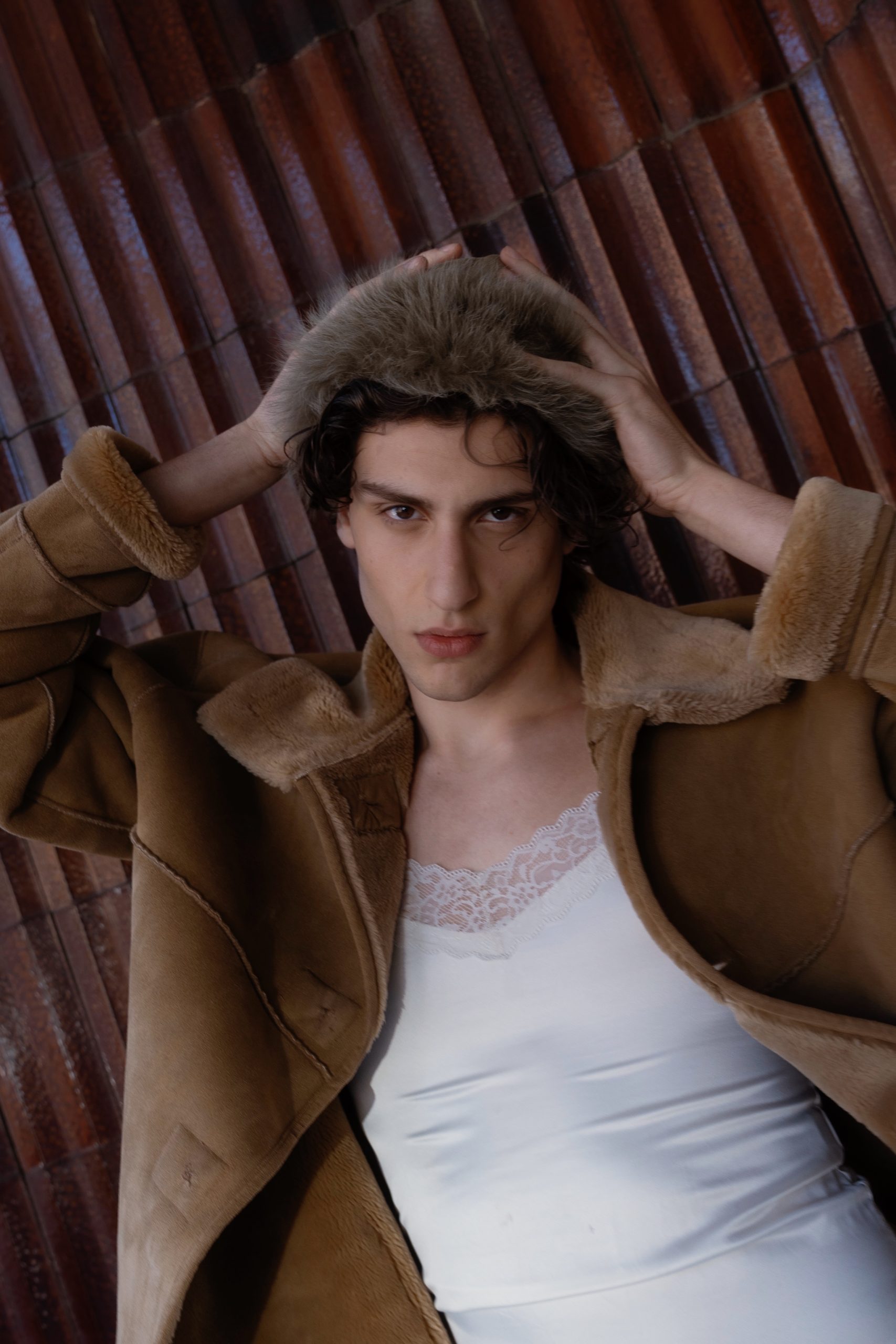 Stylish male model showcasing winter fashion in Florence, featuring a fur-lined coat and lace detail top.