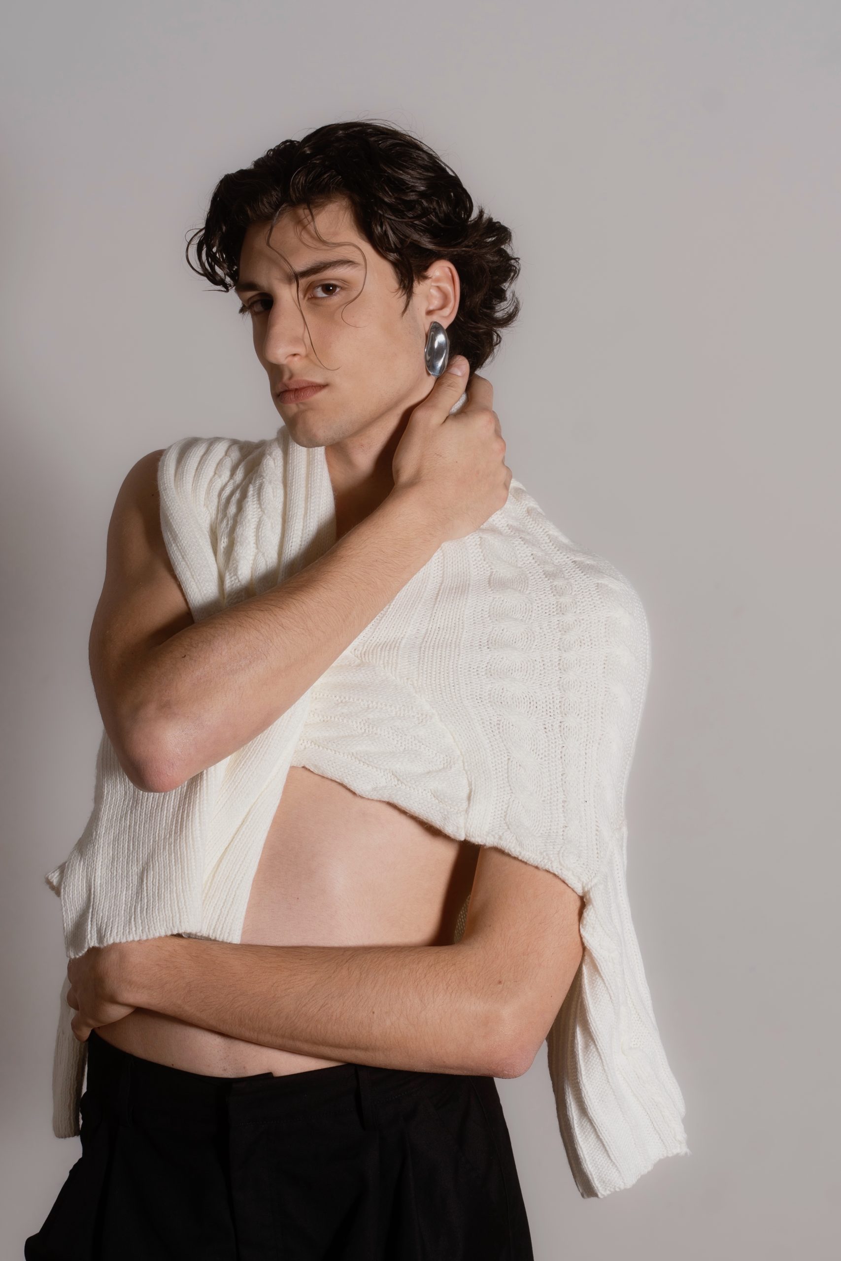 Modello maschile che indossa un maglione avvolto intorno al corpo.