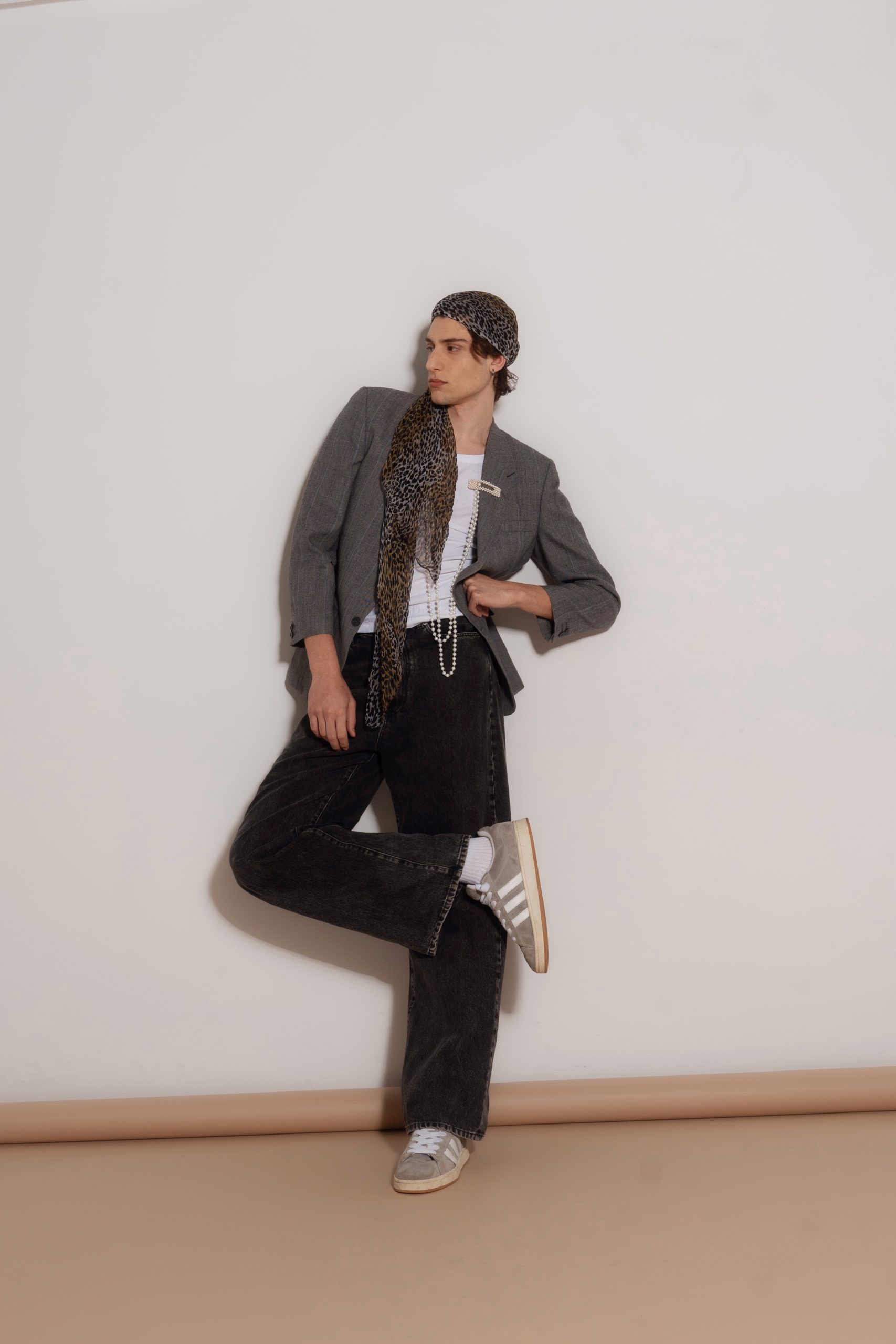 Modello maschile in blazer grigio con pantaloni neri e scarpe Adidas, stile urbano elegante