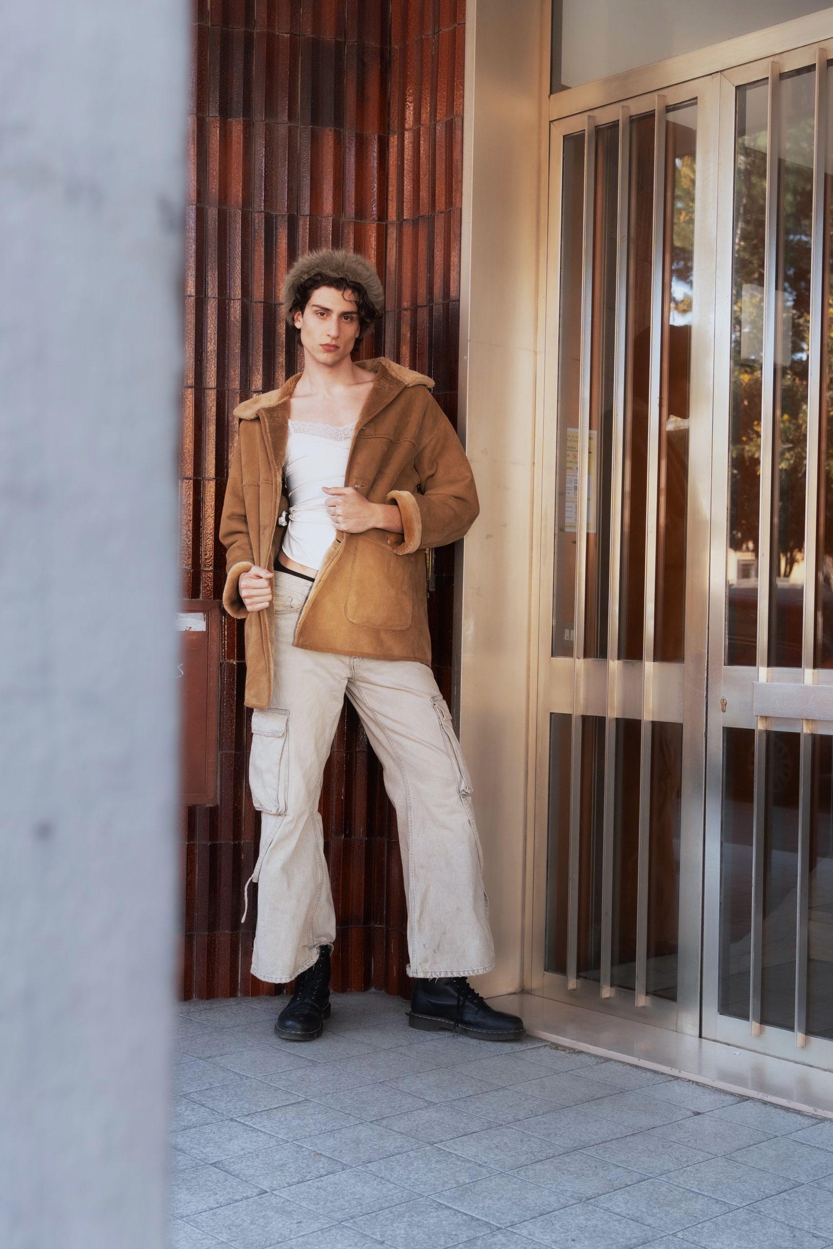 Giovane modello in giacca di pelliccia marrone e pantaloni chiari, stile urbano e alla moda.