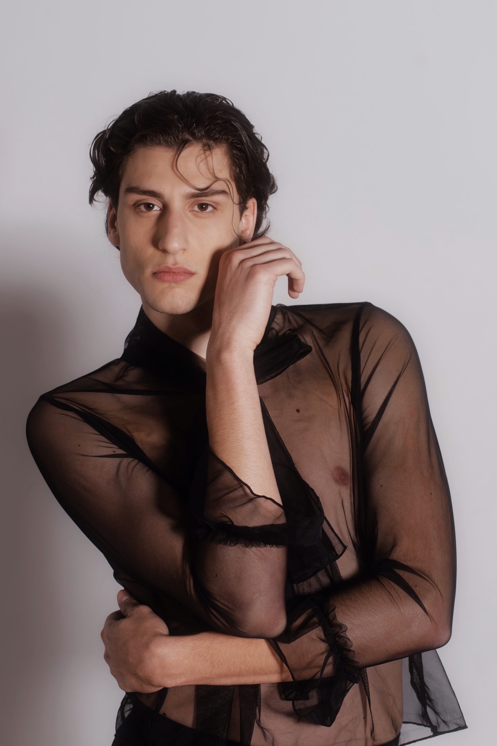 Modello maschile con camicia trasparente nera, espressione intensa e stile moderno, fotografo di moda a Firenze.