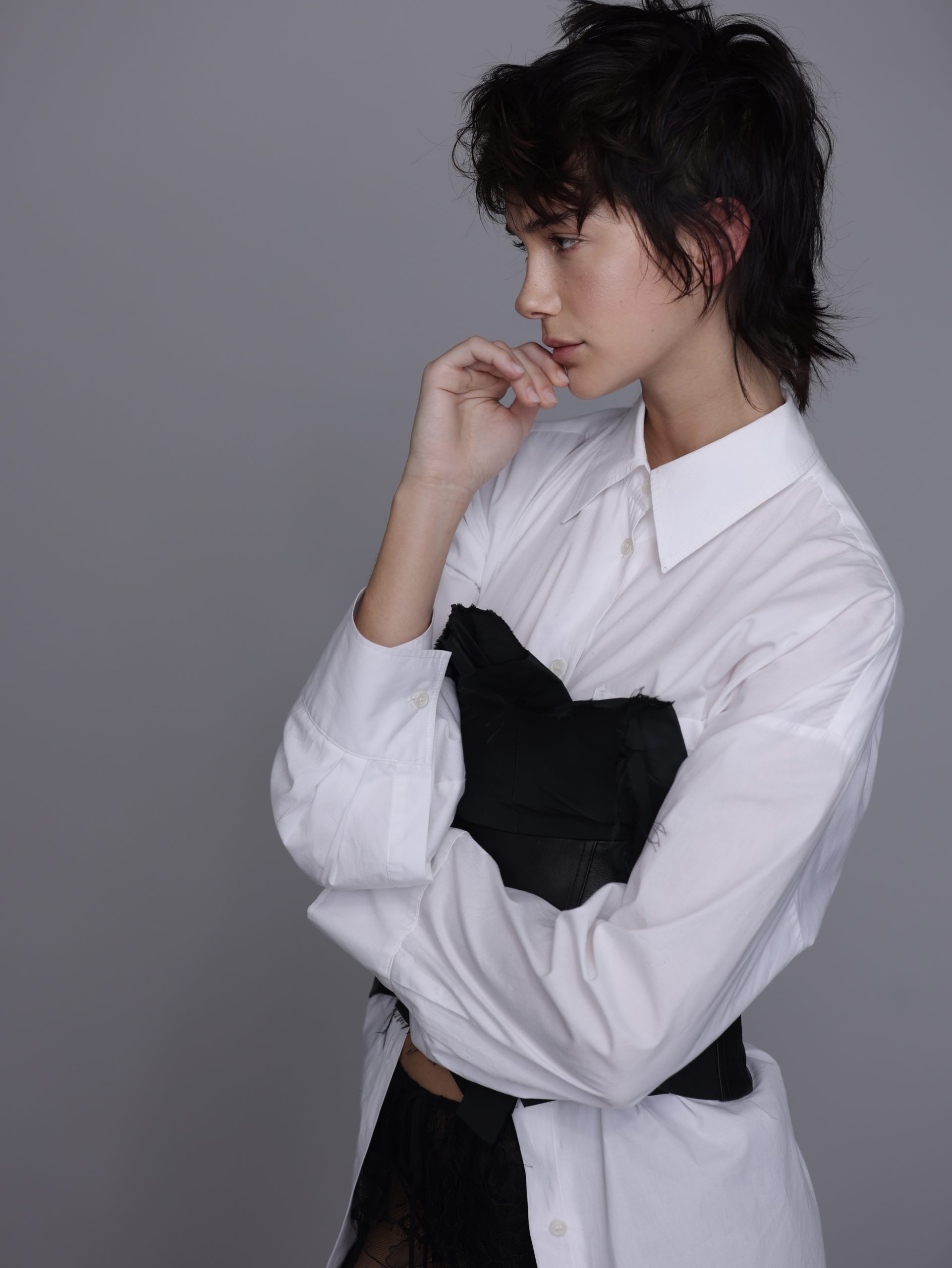 Modella con camicia bianca e corsetto nero, espressione sofisticata per collezione moda esclusiva.