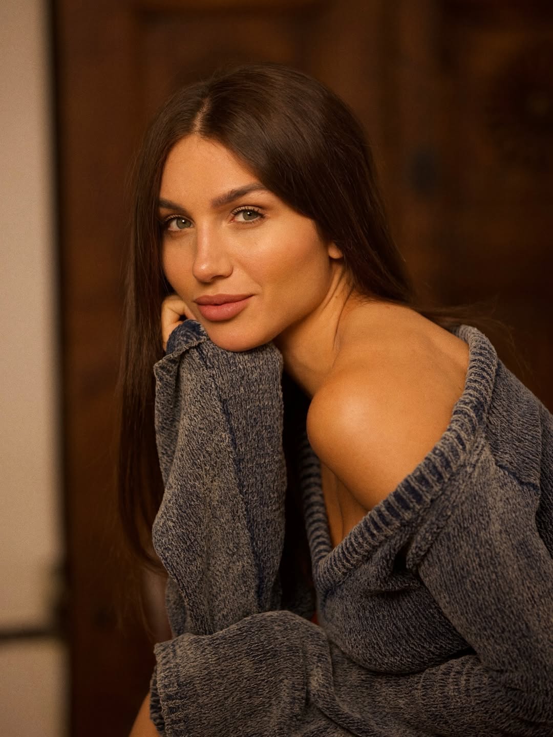 Modella in primo piano con un maglione grigio, sguardo seducente ed elegante, fotografia di moda in stile contemporaneo.