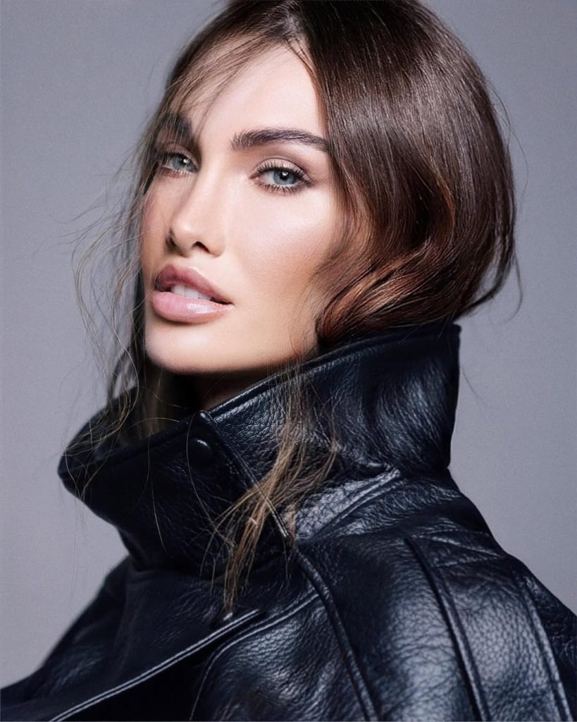 Ritratto di donna con capelli lunghi in pelle nera, espressione sofisticata, stile moda elegante.