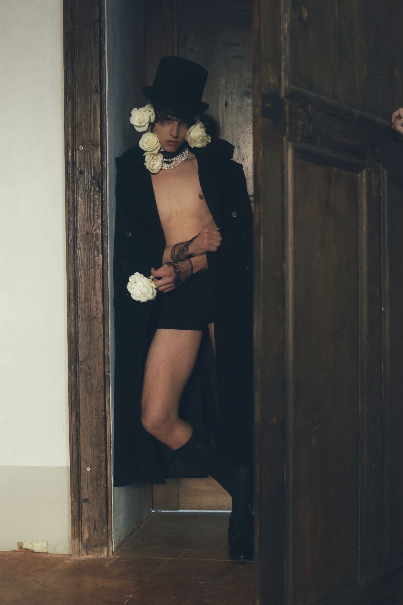 Modello maschile con cappello a cilindro e fiori, abbigliamento audace in stile fashion contemporaneo.