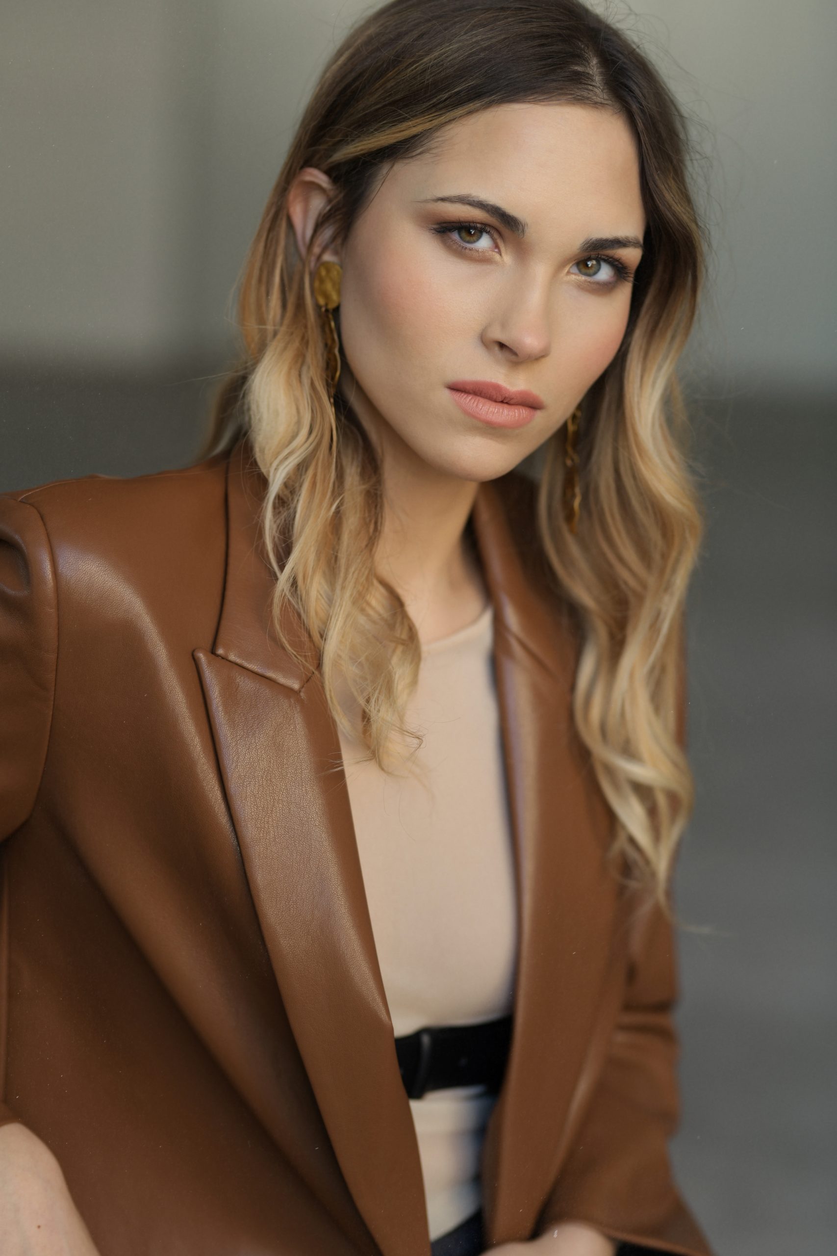 Ritratto di modella con giacca in pelle marrone e orecchini dorati, eleganza e stile a Firenze.