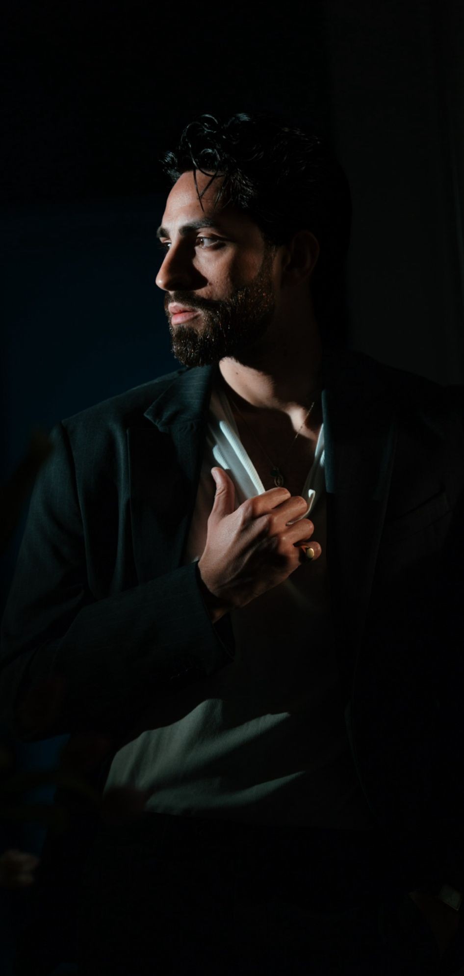 Ritratto di un modello maschile elegante con blazer, in luce soffusa che esalta il suo stile e carisma.