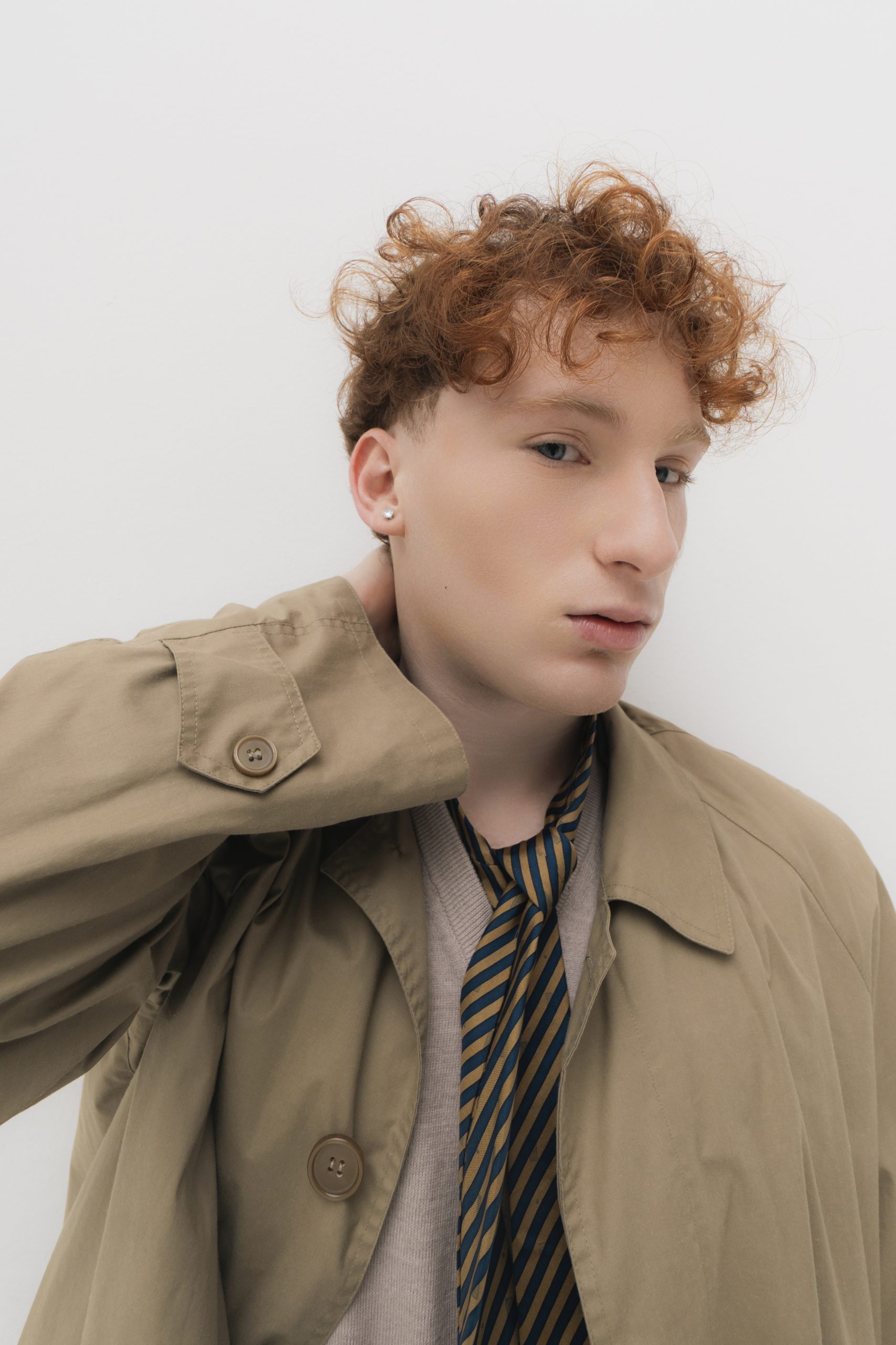 Modello giovane in posa con cappotto beige e cravatta, rappresentante Fashion Concept Firenze.