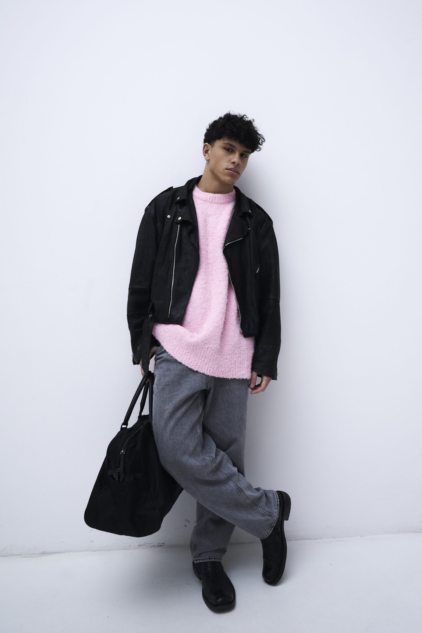 Modello maschile in outfit moderno, maglione rosa e giacca di pelle nera, moda contemporanea a Firenze.