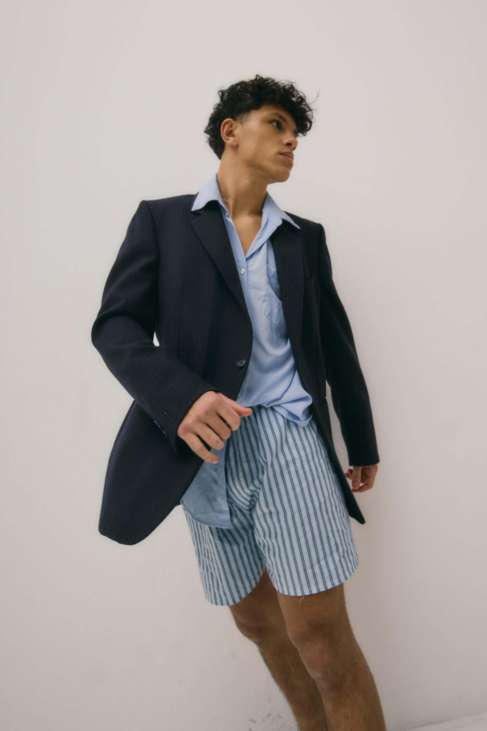 Modello maschile indossa giacca elegante blu e pantaloni a righe, stile casual sofisticato per campagne moda.