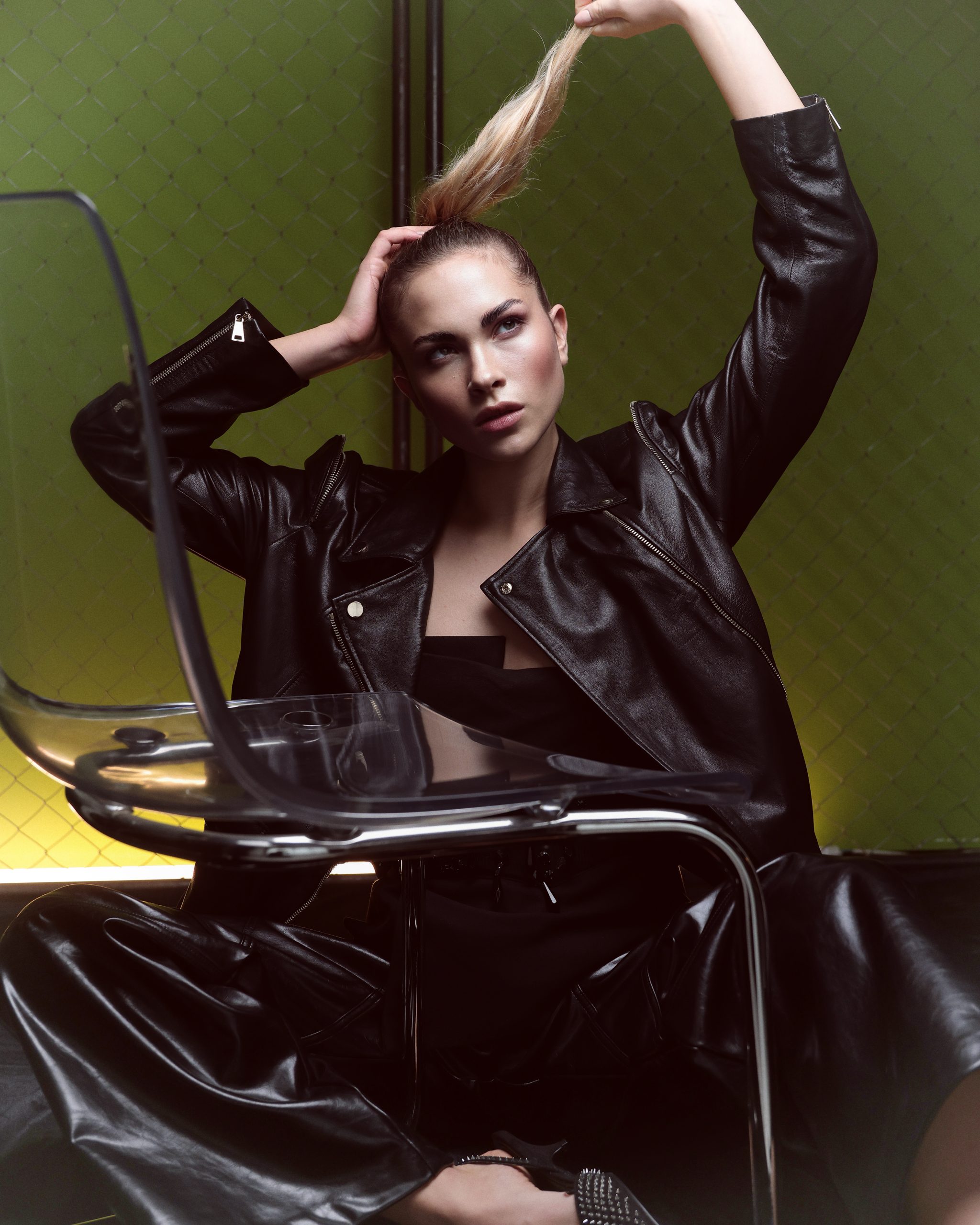Modella in giacca di pelle nera, look audace e moderno, posa elegante in uno spazio creativo.